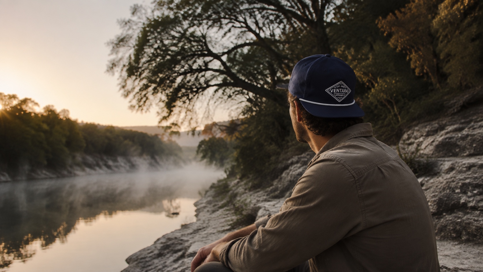 Outdoorsman wearing a navy Ventara hat beside a misty Texas river at sunrise